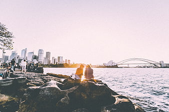 Couple sitting on rocks overlooking Sydney Opera House and Harbour Bridge