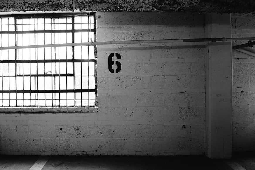 Black and white industrial wall with barred window and number 6