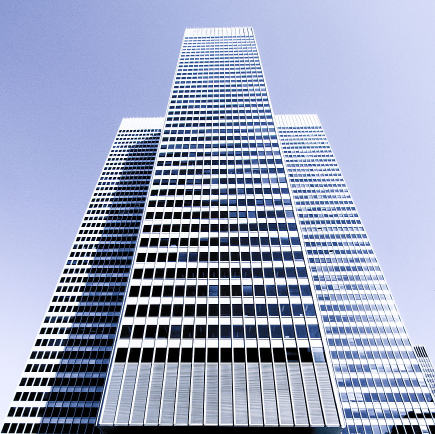 Low angle view of modern glass skyscrapers against blue sky