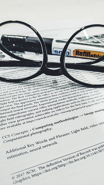 Black glasses and marker on academic research paper