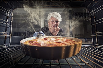 Senior Woman Placing Apple Pie Into Oven