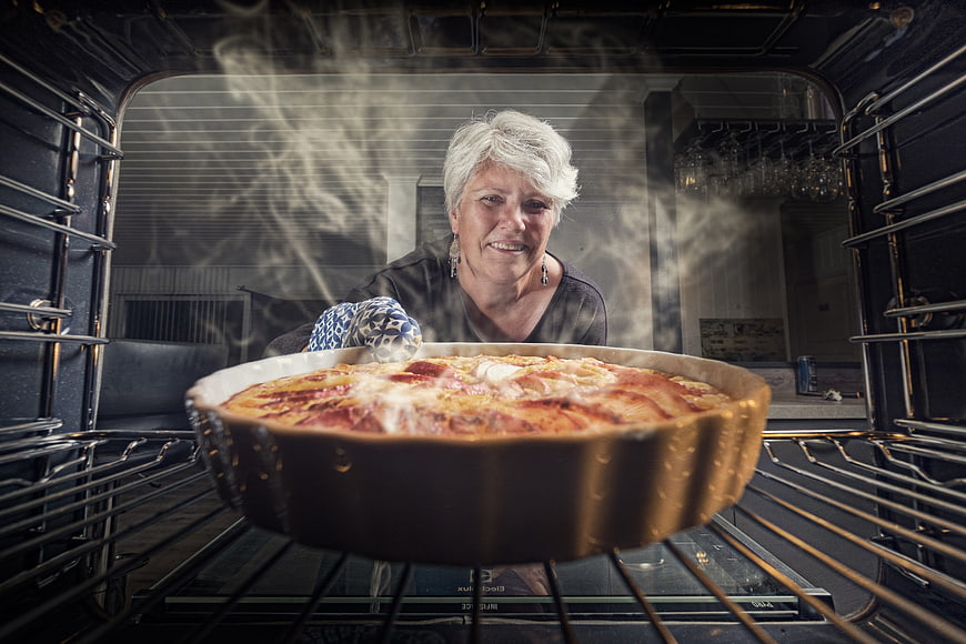 Senior Woman Placing Apple Pie Into Oven