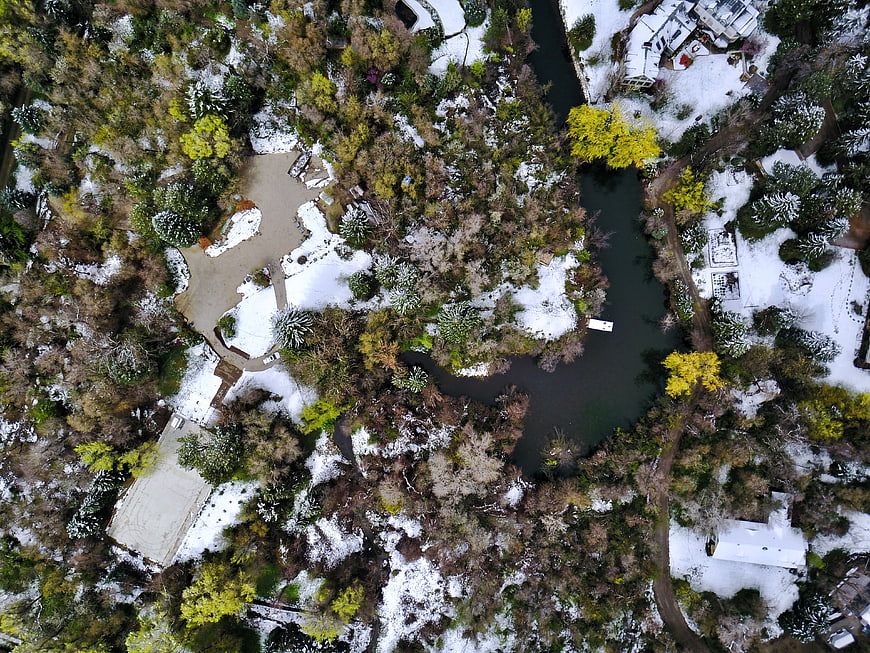 Aerial view of snowy park with winding river and trees