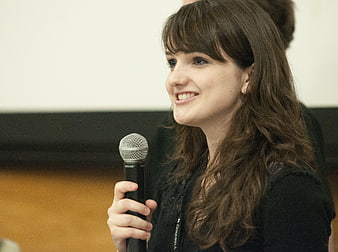 Smiling Woman Speaking into Microphone at Conference