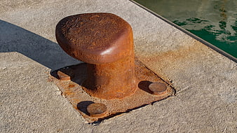 Rusty Mooring Bollard on Concrete Dock by Water