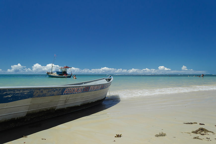 Fishing boat on white sand beach with turquoise ocean and blue sky