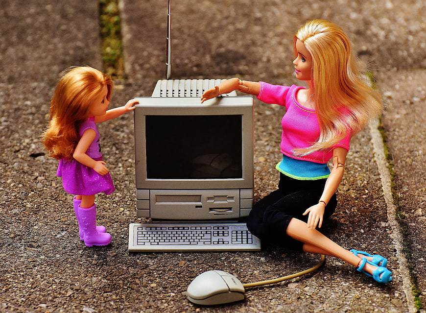 Barbie and Child Dolls Interacting with Vintage Computer on Pavement