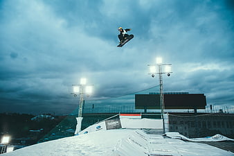 Snowboarder performing high jump at night under stadium lights