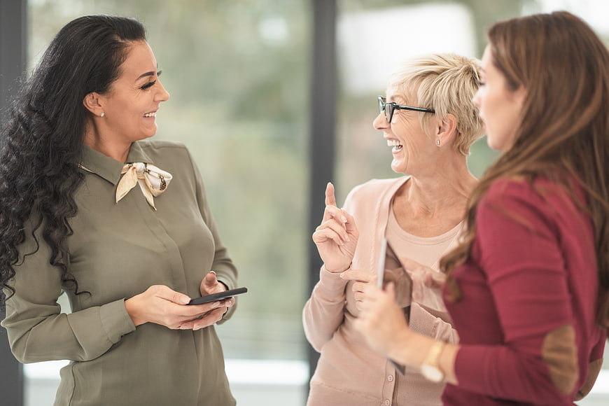 Three Women Laughing and Talking in Office