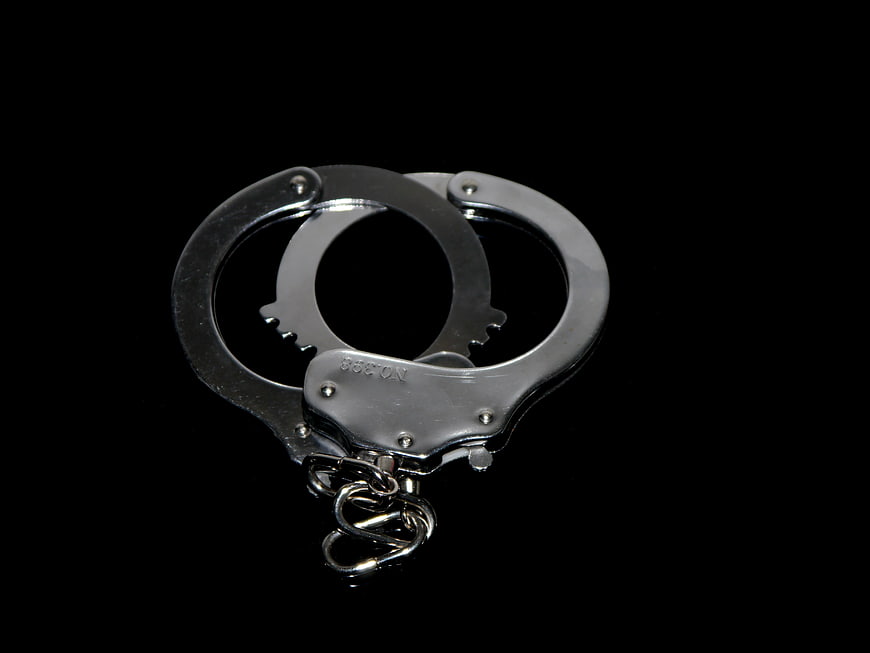 Silver handcuffs with chain on black background