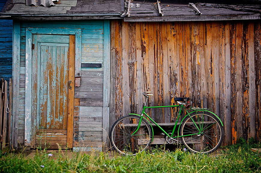 Vintage Green Bicycle Leaning Against Rustic Wooden Shed