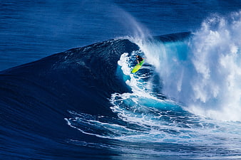 Surfer riding a massive blue ocean wave barrel