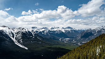 Snow-capped mountain range with green valley and blue sky