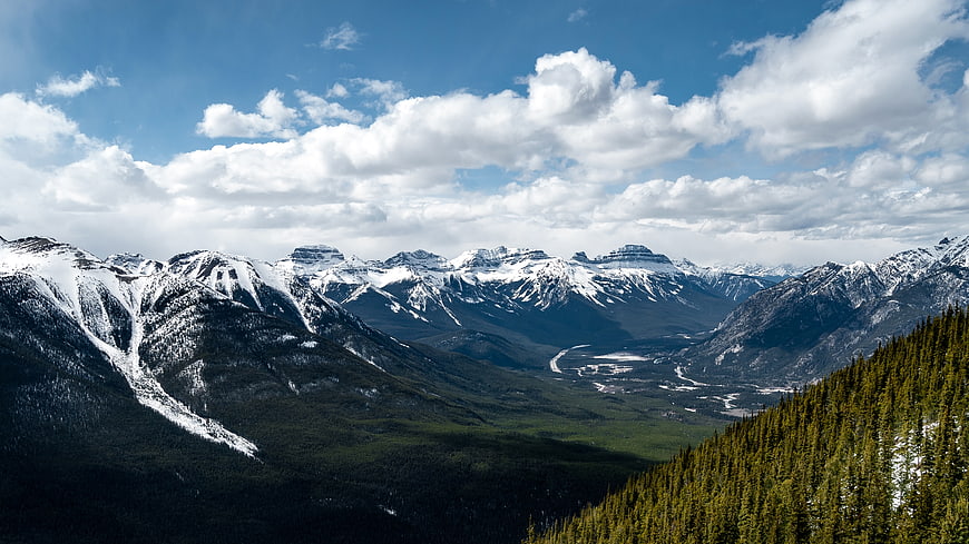 Snow-capped mountain range with green valley and blue sky