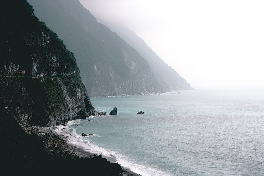 Misty coastal cliffs meeting the calm ocean sea