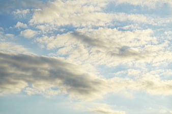Serene Blue Sky with Fluffy White Clouds and Soft Sunlight