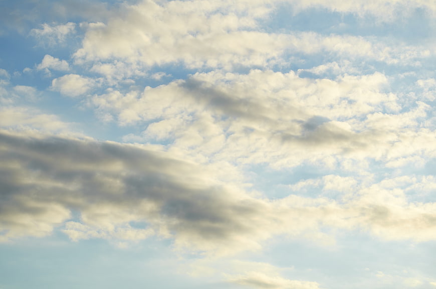 Serene Blue Sky with Fluffy White Clouds and Soft Sunlight