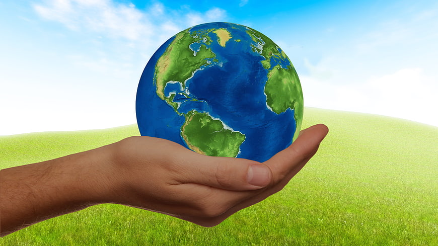 Hand holding globe on green grass background