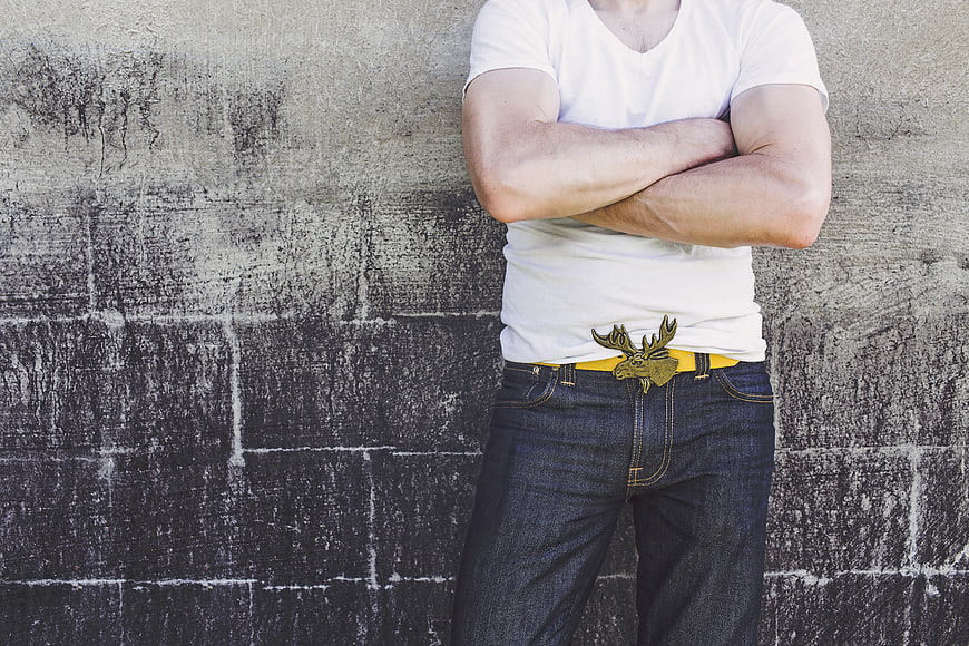 Man with Moose Belt Buckle Against Concrete Wall