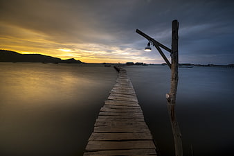 Long Exposure Wooden Pier at Sunset with Glowing Lamp