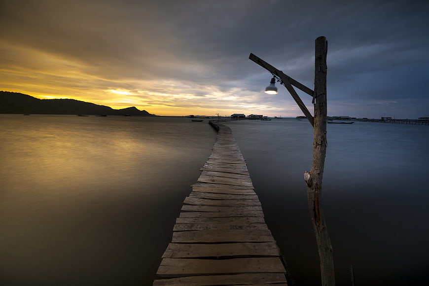 Long Exposure Wooden Pier at Sunset with Glowing Lamp