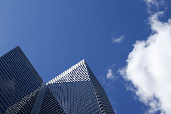 Low angle view of modern glass skyscrapers against blue sky