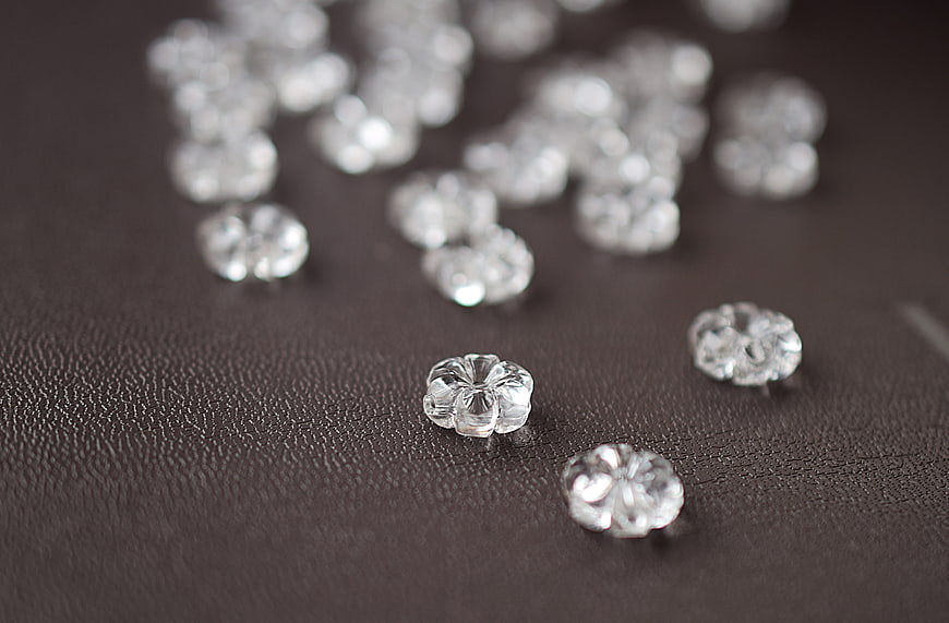 Clear glass flower beads on dark textured leather background