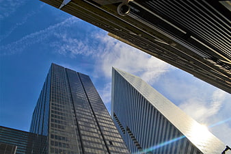 Low angle view of modern glass skyscrapers against blue sky