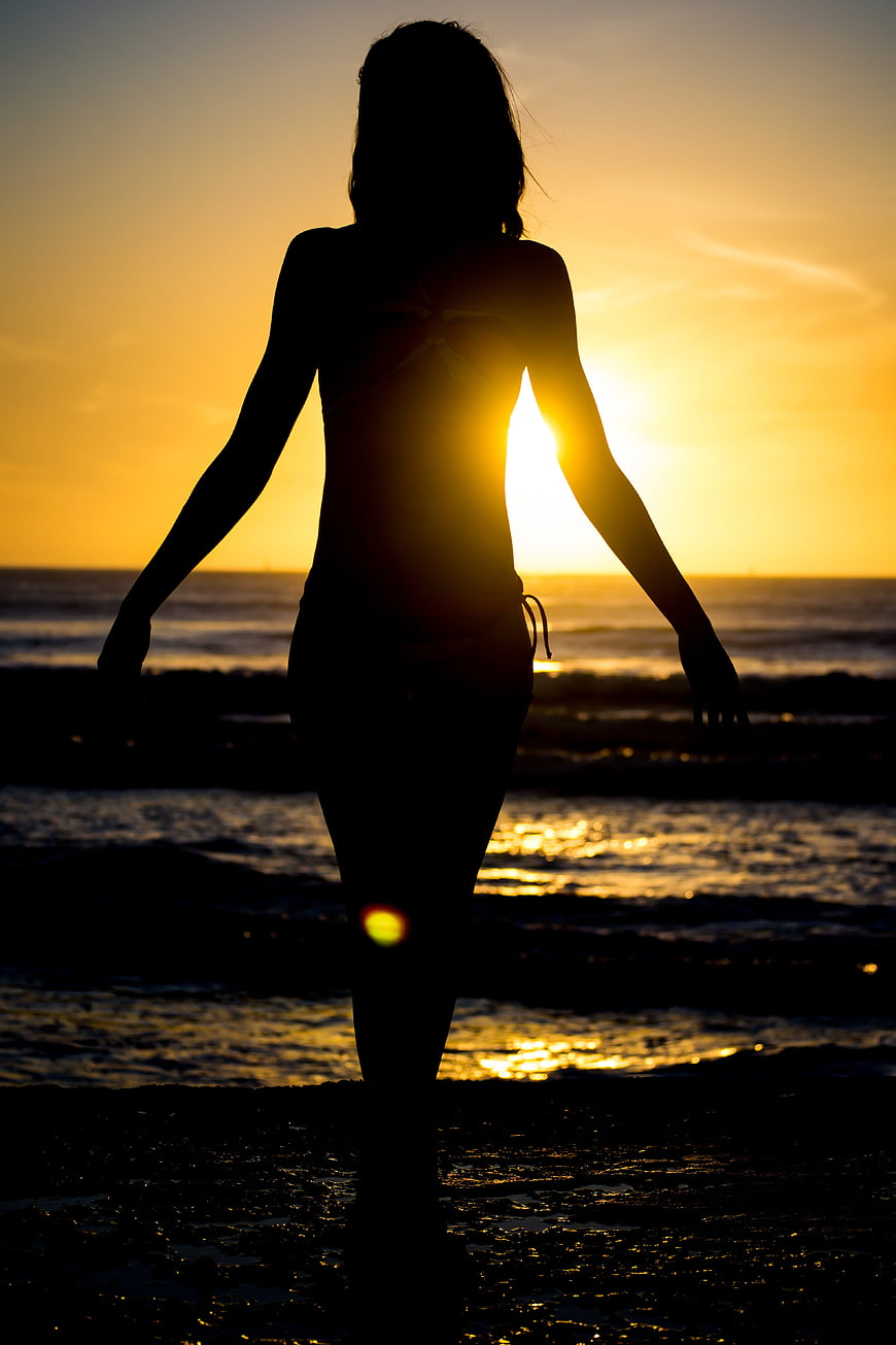 Silhouette of Woman Walking on Beach at Sunset