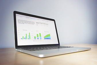 Laptop displaying business charts and graphs on wooden desk