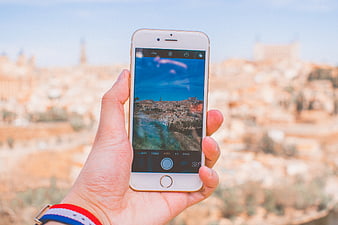 Hand holding smartphone photographing ancient cityscape