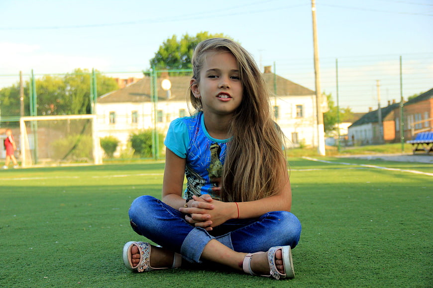 Young Girl Sitting on Artificial Turf Sports Field