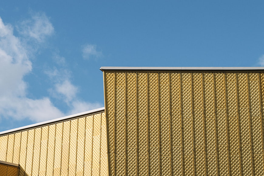 Modern gold textured building facade against blue sky
