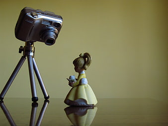 Miniature Camera Photographing Small Figurine on Reflective Surface