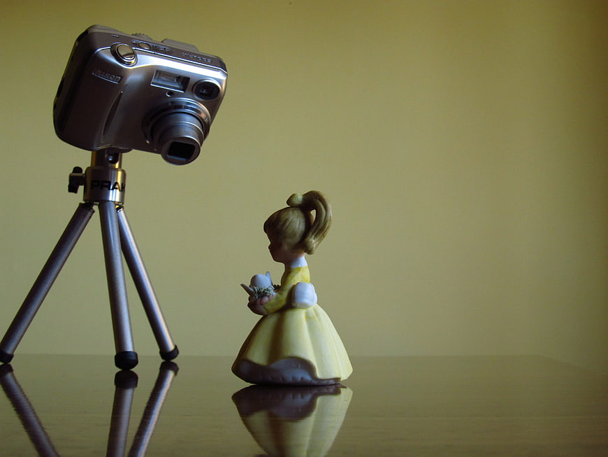 Miniature Camera Photographing Small Figurine on Reflective Surface