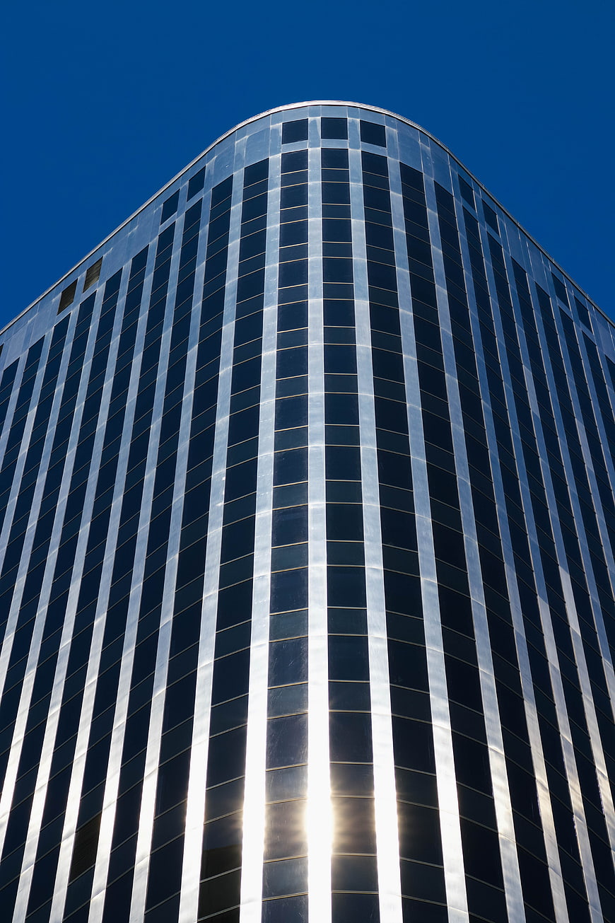 Low angle view of modern glass skyscraper against blue sky