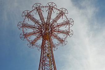 Low angle view of red steel parachute jump tower against blue sky
