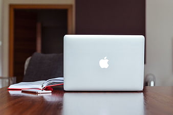 Closed MacBook, iPhone, and Notebook on Wooden Desk