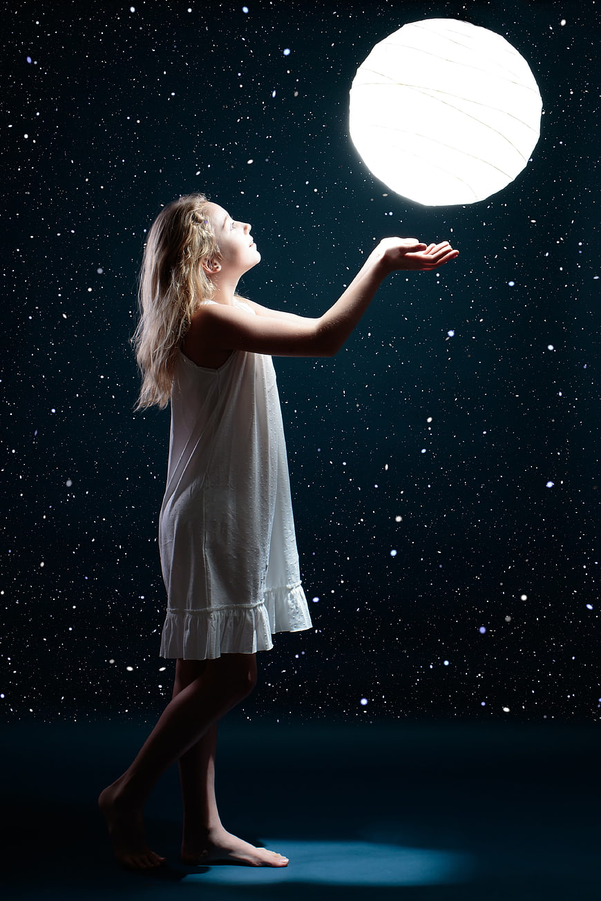 Young Girl Reaching for Glowing Moon in Starry Night