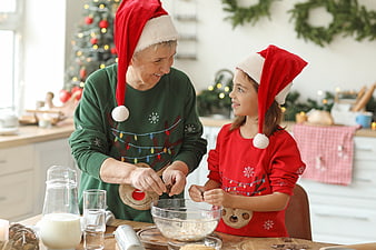 Grandmother and granddaughter baking Christmas cookies in festive kitchen