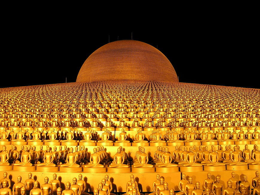 Golden Buddha statues arranged in rows before a large dome at night