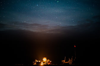 Group of friends camping under starry night sky with jeep