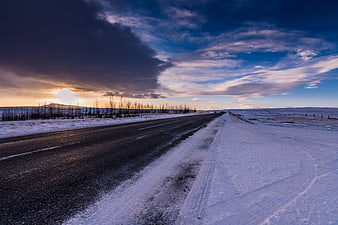 Snowy Winter Road at Sunset with Dramatic Clouds