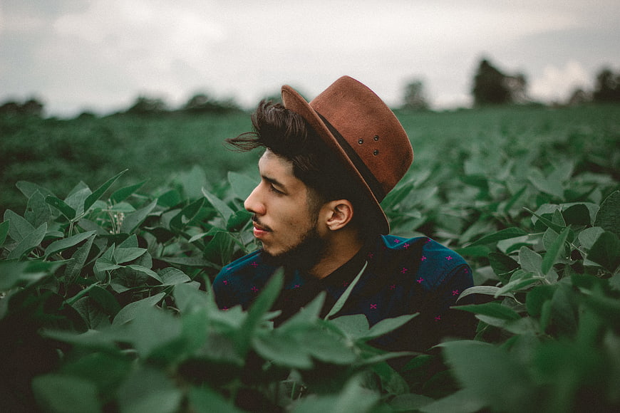 Man in Fedora Hat Sitting in Green Soybean Field