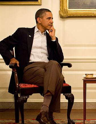 Barack Obama seated in a thoughtful pose in a formal room