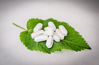 White pills on green leaf for natural medicine concept