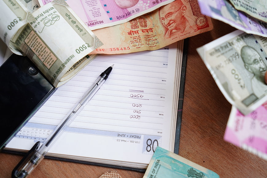 Indian Rupee Banknotes On Planner With Pen And Mobile Phone
