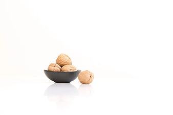 Walnuts in a black bowl on white background