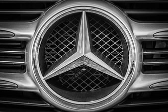 Black and White Close-Up of Mercedes-Benz Star Emblem on Chrome Car Grille