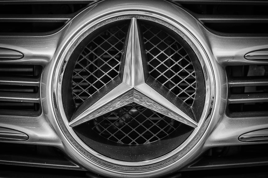 Black and White Close-Up of Mercedes-Benz Star Emblem on Chrome Car Grille